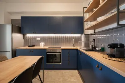 a kitchen with blue cabinets and a wooden table at ☆Kalimarmaro 3BD Apt For Max Fun & Comfortability☆ in Athens
