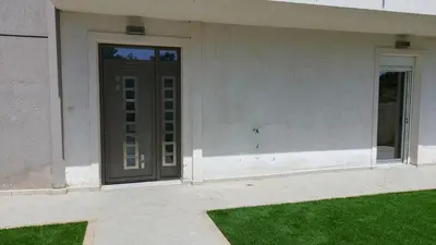 a door on the side of a building with green grass at Gianni & Sophia airport house in Artemida
