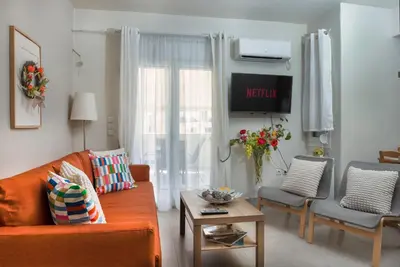 a living room with an orange couch and a tv at The Athenian Penthouse Residence in Athens