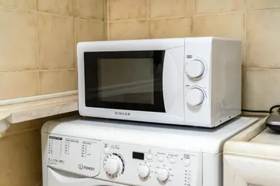 a white microwave sitting on top of a appliance at Cozy Studio by the sea in Paleo Faliro in Athens