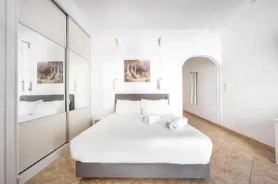 a white bedroom with a large bed and mirrors at Cozy Studio by the sea in Paleo Faliro in Athens