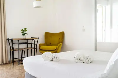 a room with a bed and a yellow chair at Cozy Studio by the sea in Paleo Faliro in Athens
