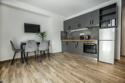 a kitchen with a table and two chairs and a refrigerator at Raise Averof Serviced Apartments in Athens