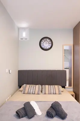 a bedroom with a large bed with a clock on the wall at AIOLOS LUXURY alimos quiet apartment 1 in Athens
