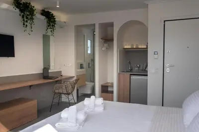 a bedroom with a white bed and a kitchen at Athens Glance Boutique Apartments in Athens