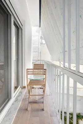 a wooden chair sitting on a balcony with windows at Nazar Apartment- in the center of Athens in Athens
