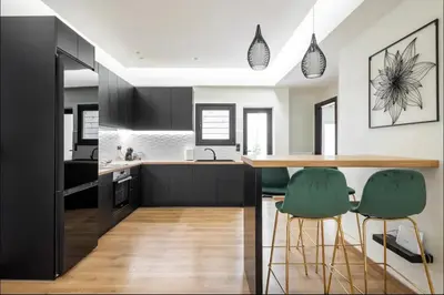 a kitchen with black cabinets and green bar stools at Nazar Apartment- in the center of Athens in Athens