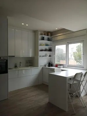 a kitchen with white cabinets and a table and a window at Riviera Studio in Athens