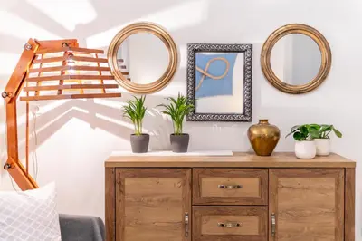 a room with two mirrors and a wooden dresser with plants on it at Petralona's Green House in Athens