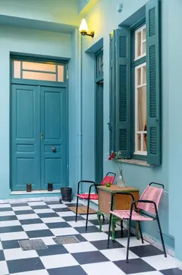 a porch with two chairs and a table and a blue door at Petralona's Green House in Athens