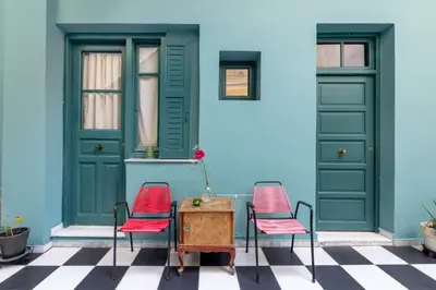 two chairs and a table in front of a blue house at Petralona's Green House in Athens