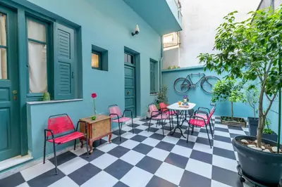a patio with pink chairs and a table on a checkered floor at Petralona's Green House in Athens