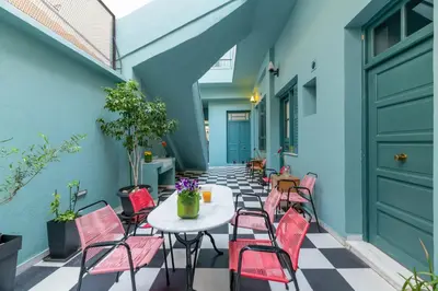 a patio with pink chairs and a white table at Petralona's Green House in Athens