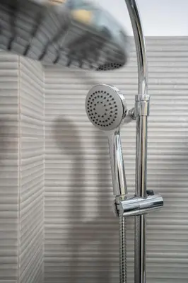 a chrome shower head in a bathroom with a person at Ag Ioannis m station 1 bed for 2 pers by MPS in Athens