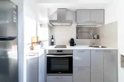 a white kitchen with a stove and a sink at Luxury penthouse , breathtaking Acropolis view in Athens