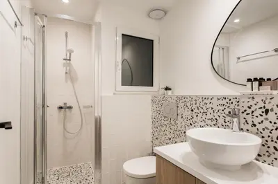 a white bathroom with a sink and a shower at Dazzling 1BR Apartment in Koukaki by UPSTREET in Athens