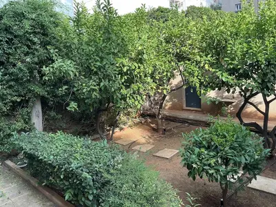 a garden with trees and bushes in front of a house at 2BDRM Glyfada Residence - Jacuzzi, Garden & Parking in Athens