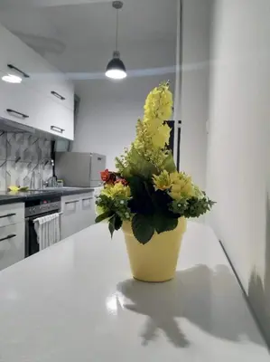 a yellow vase with flowers on a counter in a kitchen at A convenient apartment in the heart of Athens in Athens