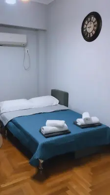 a bedroom with a bed with a clock on the wall at A convenient apartment in the heart of Athens in Athens