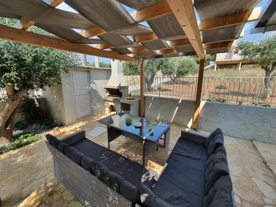a patio with a couch and a table under a pergola at Jasmine Villa in Vari