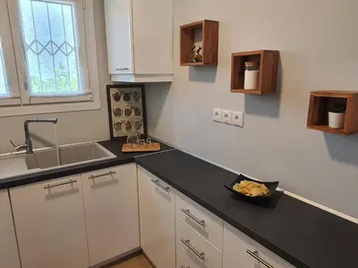 a kitchen with white cabinets and a black counter top at Jasmine Villa in Vari