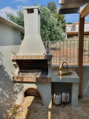 an outdoor grill with a brick oven in a yard at Jasmine Villa in Vari