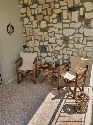 two chairs and a table in front of a stone wall at Jasmine Villa in Vari