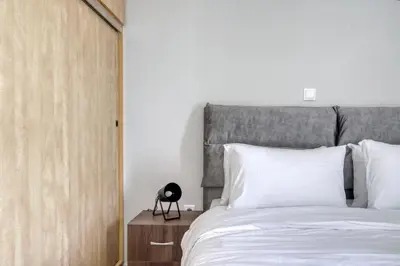 a bedroom with a white bed with a gray headboard at Sunny & cosy apt with balcony in Peristeri! in Athens