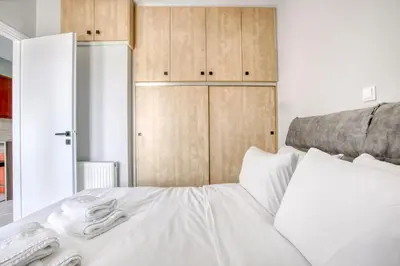a bedroom with a white bed with wooden cabinets at Sunny & cosy apt with balcony in Peristeri! in Athens