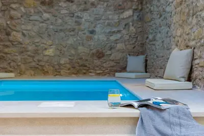 a glass of water sitting next to a swimming pool at Incomparable Plaka's Luxury Apt Private Pool in Athens