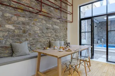 a dining room with a table and a stone wall at Incomparable Plaka's Luxury Apt Private Pool in Athens