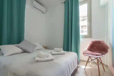 a bedroom with a bed with a chair and a window at Aphrodite Apartment in Athens
