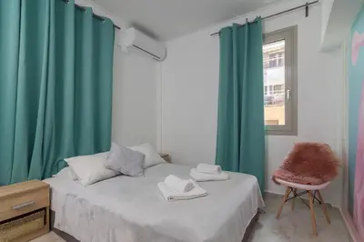 a bedroom with two beds with green curtains and a chair at Aphrodite Apartment in Athens