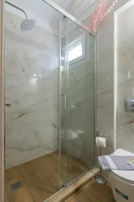 a glass shower in a bathroom with a toilet at Aphrodite Apartment in Athens
