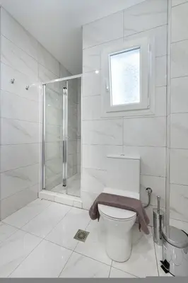 a white bathroom with a toilet and a shower at Porto Pireo By SuperHost365 Kolokotroni in Piraeus