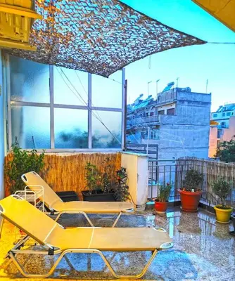 a patio with two chairs and an umbrella at Koukaki sunshine roof apartment in Athens
