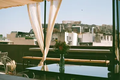 a table with a vase of flowers on a balcony at Mona Athens in Athens