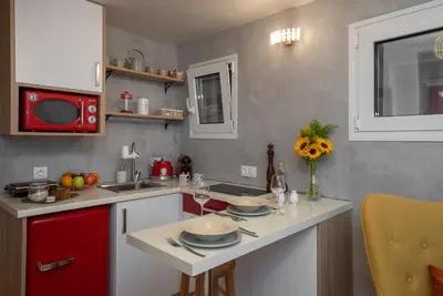 a kitchen with red cabinets and a white counter top at Cozy tiny apartment in the heart of Plaka in Athens