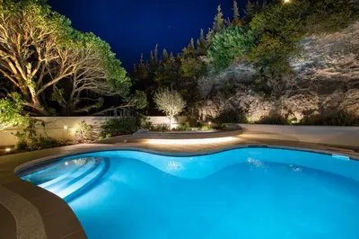 a swimming pool in a garden at night at LazySun in Sounio