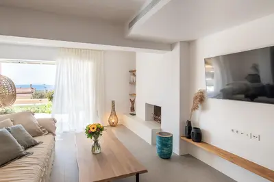 a white living room with a couch and a table at LazySun in Sounio