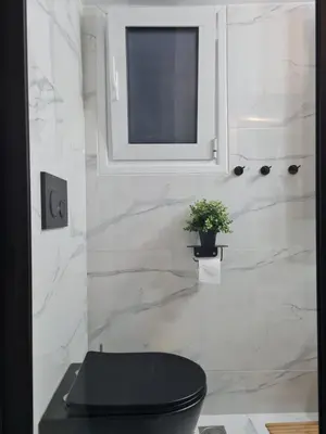 a bathroom with a black toilet and a window at Jenny's Dream Home -Acropolis Lux 2 Bedroom Apt, with Hot Tub, free Netflix, fast Wifi in Athens