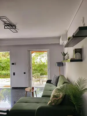 a living room with a green couch and a window at Modern Garden View Apt in Voula, Athens - Luxe in Athens