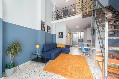 a living room with a blue couch and a staircase at Athens Loft in Athens