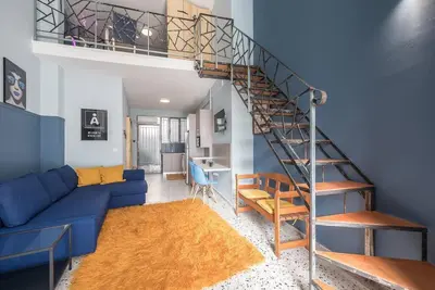 a living room with a blue couch and a spiral staircase at Athens Loft in Athens