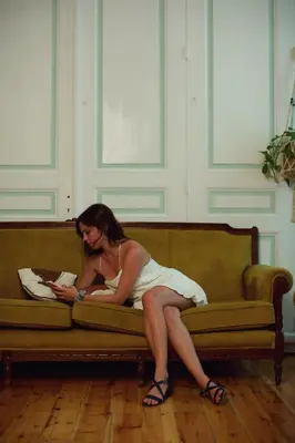a woman sitting on a couch reading a book at Baloo Hostel in Athens