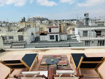 a balcony with chairs and a table on a roof at 200Mbps Wifi - Penthouse With Acropolis View in Athens