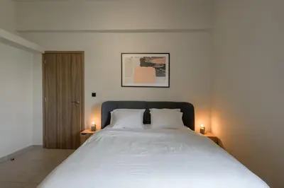 a bedroom with a large white bed with two candles at Galio Suites Airport by Airstay in Spáta