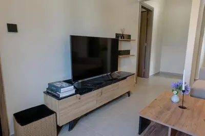 a living room with a large flat screen tv on a wooden entertainment center at Galio Suites Airport by Airstay in Spáta