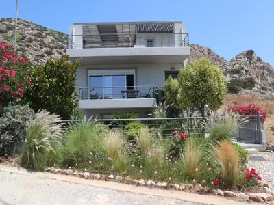 a house with flowers in front of a mountain at Patroclos SeaView in Sounio