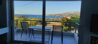 a table and chairs on a balcony with a view of the ocean at Patroclos SeaView in Sounio